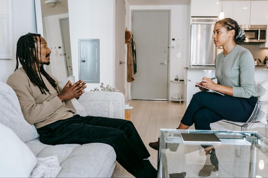 Therapist talking notes speaking to a patient in a treatment center about mental health